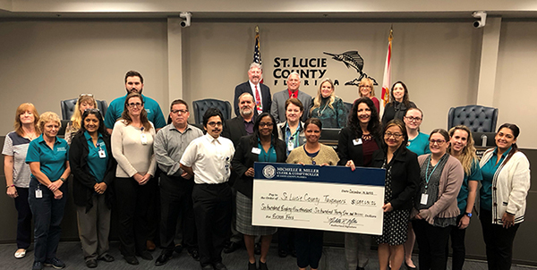 Photo Caption: Clerk Michelle Miller presents a check to the St. Lucie County Board of County Commissioners with the Clerk Finance Department.